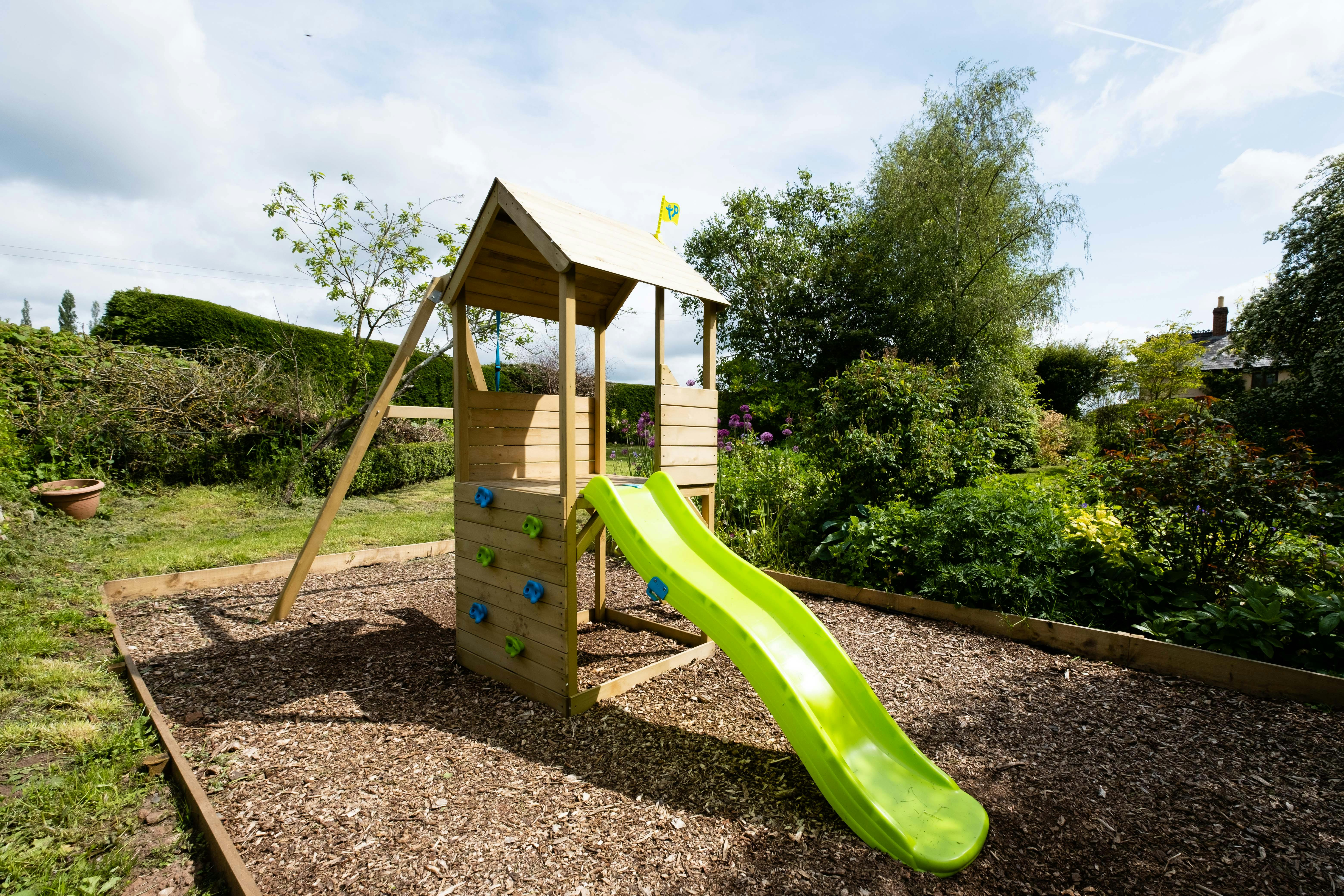 A children's backyard playset with swings and a slide.